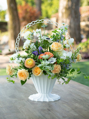 Fluted White Plastic Basket with flowers sitting on a wood table